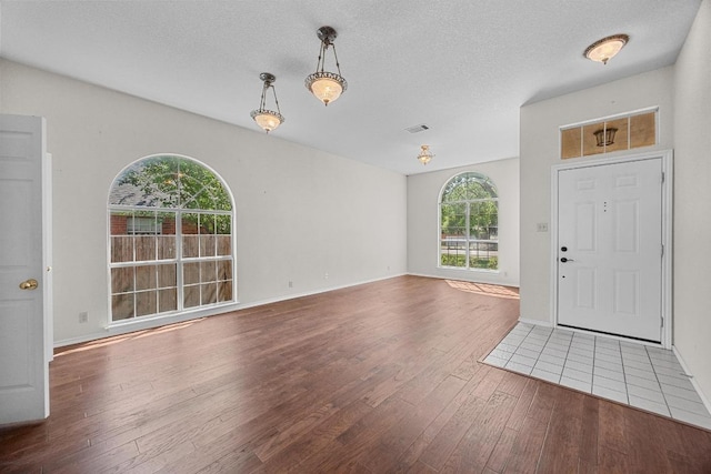 foyer with visible vents, baseboards, hardwood / wood-style flooring, and a textured ceiling