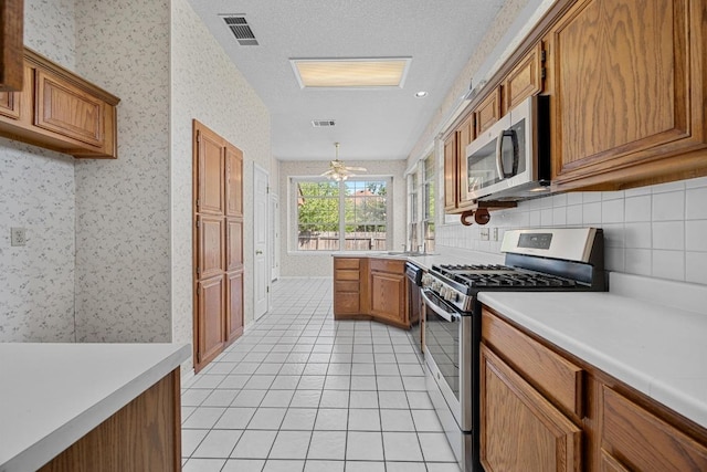 kitchen with brown cabinetry, visible vents, light countertops, stainless steel appliances, and backsplash