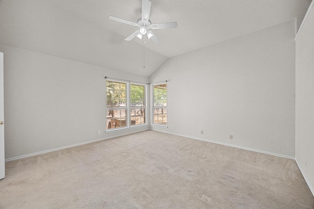 carpeted empty room with ceiling fan, vaulted ceiling, and baseboards