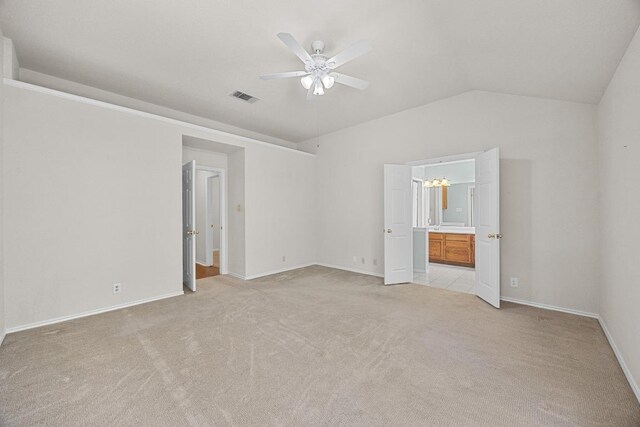 unfurnished bedroom featuring visible vents, light colored carpet, baseboards, and lofted ceiling