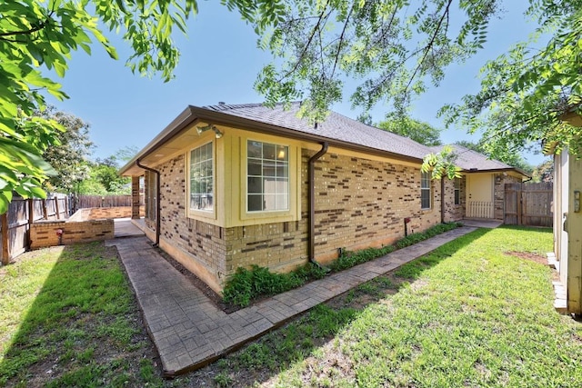view of property exterior with a yard, a fenced backyard, and brick siding