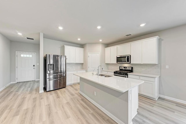 1528 Longhorn Ranch Dr, Leander, TX 78641 - kitchen featuring appliances with stainless steel finishes, decorative backsplash, white cabinetry, light countertops, and light wood-style flooring
