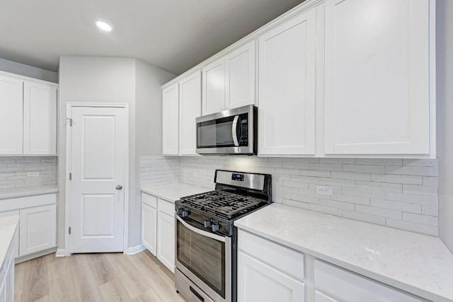 1528 Longhorn Ranch Dr, Leander, TX 78641 - kitchen featuring stainless steel appliances, decorative backsplash, white cabinets, light wood-type flooring, and light stone countertops