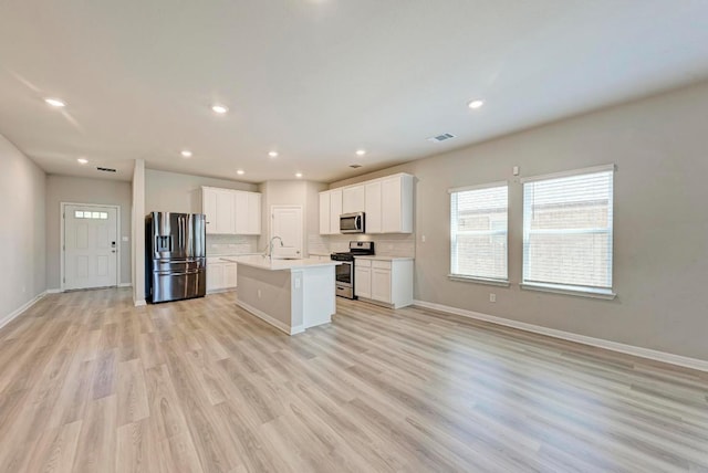 1528 Longhorn Ranch Dr, Leander, TX 78641 - kitchen featuring appliances with stainless steel finishes, open floor plan, light countertops, a center island with sink, and light wood-type flooring