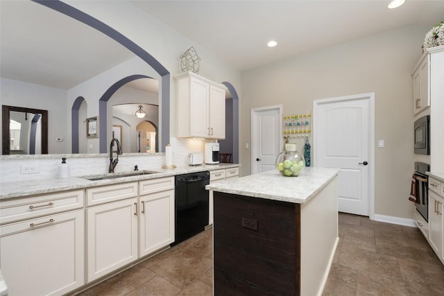 109 Lombardia Dr, Lakeway, TX 78734 - kitchen with black appliances, a center island, light stone counters, arched walkways, and white cabinetry