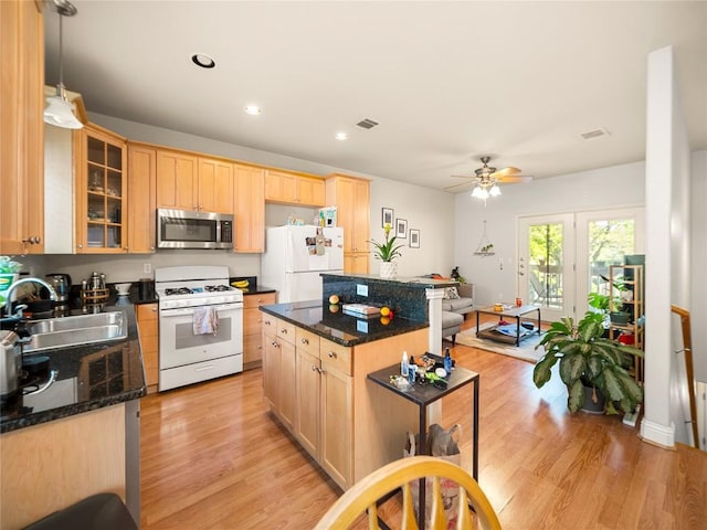 kitchen featuring white appliances, a ceiling fan, a sink, and light brown cabinetry