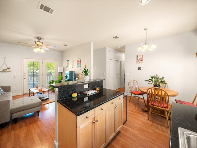 kitchen with light wood-type flooring, open floor plan, a center island, visible vents, and ceiling fan