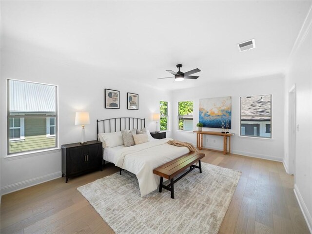 bedroom featuring ceiling fan, light wood finished floors, baseboards, and visible vents