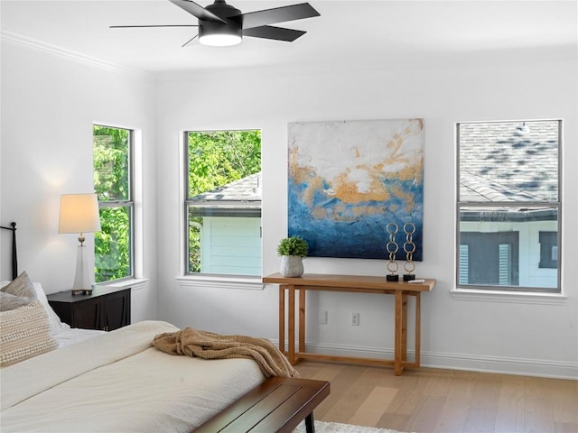 bedroom featuring ceiling fan, baseboards, crown molding, and wood finished floors