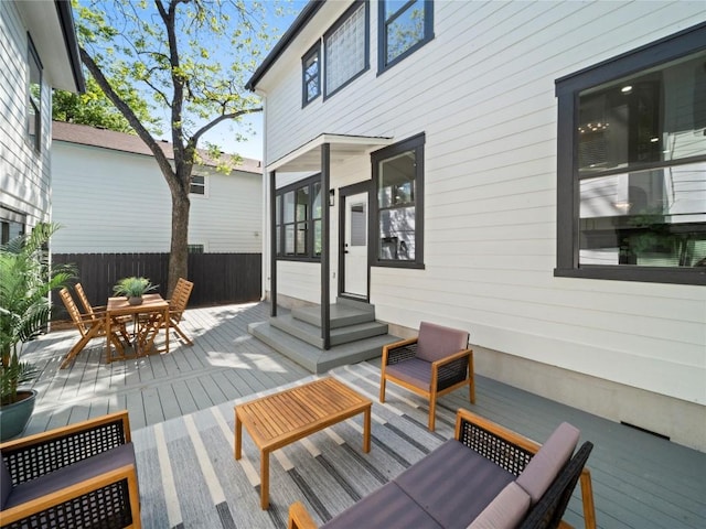 wooden deck featuring entry steps, outdoor dining space, fence, and a sunroom