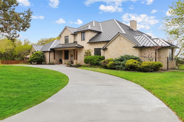 view of front of property with a standing seam roof, a front yard, fence, and metal roof