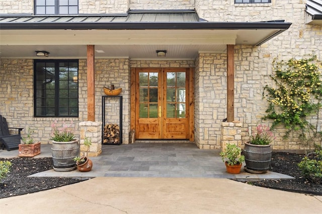doorway to property with french doors, a standing seam roof, and stone siding
