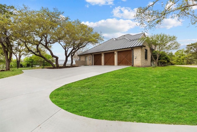 view of side of home featuring stone siding, metal roof, fence, concrete driveway, and a standing seam roof