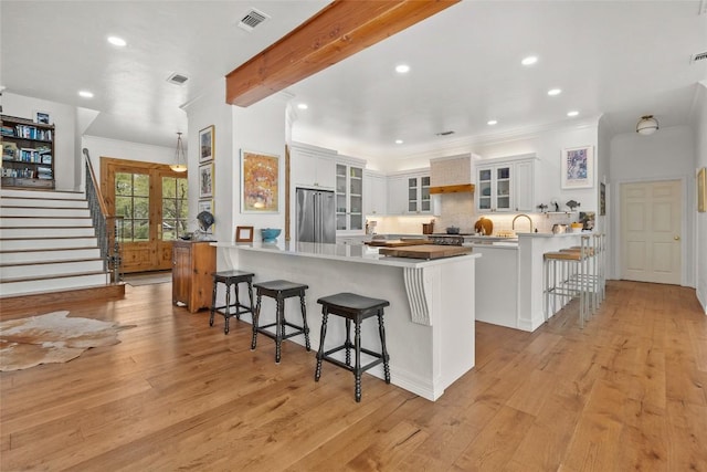 kitchen featuring high end refrigerator, a peninsula, visible vents, and a kitchen breakfast bar