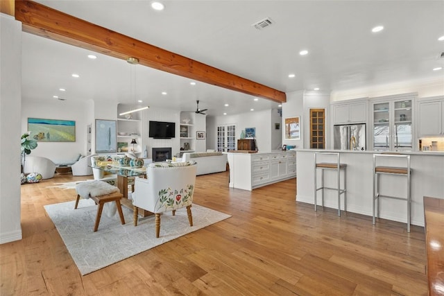 living area with beamed ceiling, a fireplace, visible vents, and recessed lighting