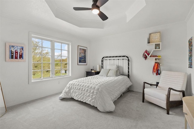 carpeted bedroom with baseboards, a tray ceiling, ornamental molding, and a ceiling fan