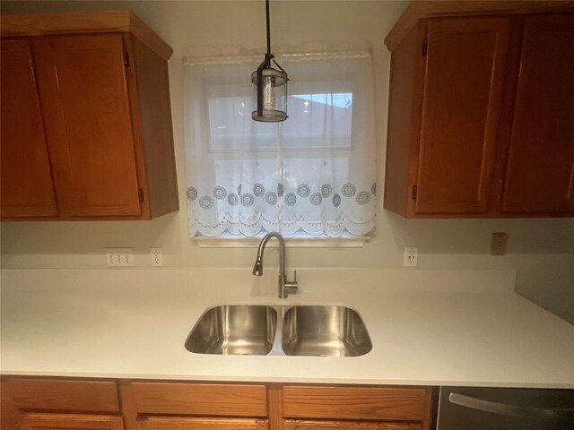 506 Clearcreek Dr, Leander, TX 78641 - kitchen featuring a sink, stainless steel dishwasher, light countertops, brown cabinets, and hanging light fixtures