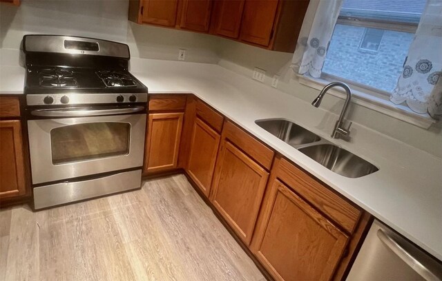 506 Clearcreek Dr, Leander, TX 78641 - kitchen featuring stainless steel appliances, a sink, brown cabinetry, light countertops, and light wood-style flooring