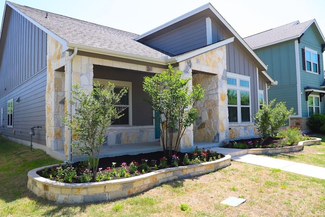8801 Mina Dr, Austin, TX 78747 - view of side of property with stone siding, board and batten siding, and covered porch