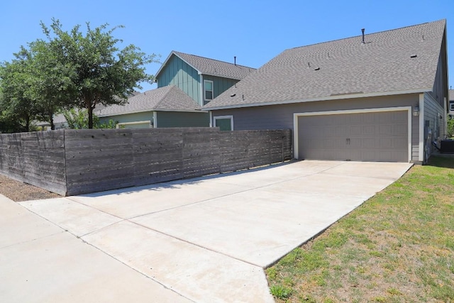 8801 Mina Dr, Austin, TX 78747 - view of home's exterior with concrete driveway, a shingled roof, board and batten siding, and an attached garage