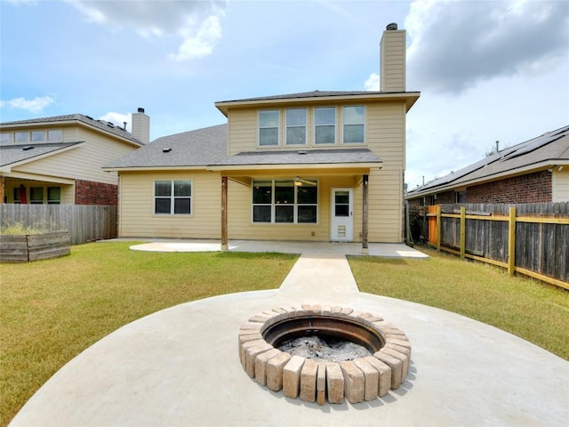 rear view of property featuring a fire pit, a patio, a fenced backyard, and a yard
