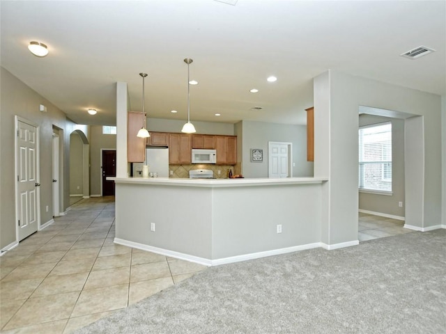 kitchen with brown cabinetry, white appliances, visible vents, backsplash, and arched walkways