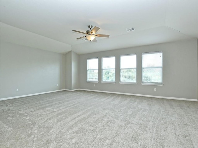 carpeted empty room with ceiling fan, lofted ceiling, baseboards, and visible vents