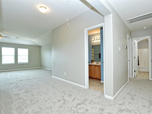 empty room with attic access, visible vents, light carpet, a ceiling fan, and baseboards