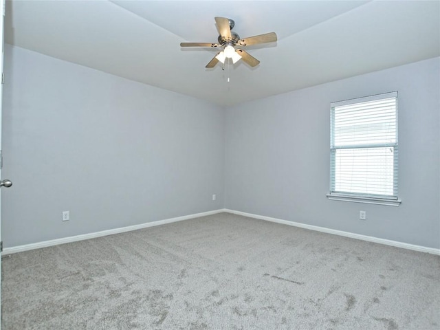 carpeted spare room featuring baseboards and ceiling fan