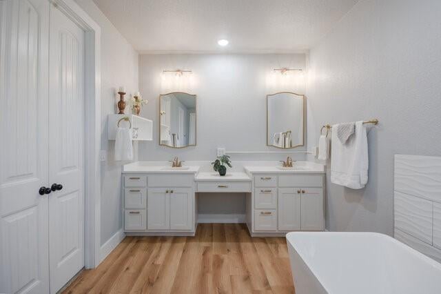3401 Bandit Ct, Kempner, TX 76539 - bathroom with double vanity, a soaking tub, wood finished floors, and recessed lighting