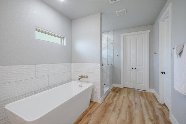 3401 Bandit Ct, Kempner, TX 76539 - full bathroom featuring a soaking tub, wood finished floors, and a shower stall