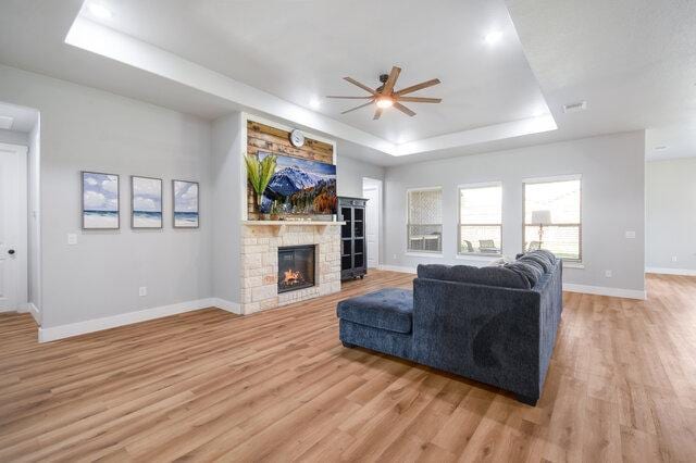 3401 Bandit Ct, Kempner, TX 76539 - living room with a tray ceiling, a ceiling fan, light wood-style flooring, and a fireplace