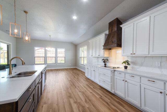 3401 Bandit Ct, Kempner, TX 76539 - kitchen featuring custom range hood, black electric stovetop, light wood finished floors, light countertops, and white cabinets