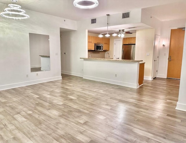 603 Davis St Unit 804, Austin, TX 78701 - unfurnished living room featuring light wood-style floors, baseboards, a sink, ceiling fan, and a chandelier