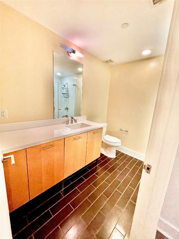 603 Davis St Unit 804, Austin, TX 78701 - full bathroom with vanity, toilet, a shower, and baseboards