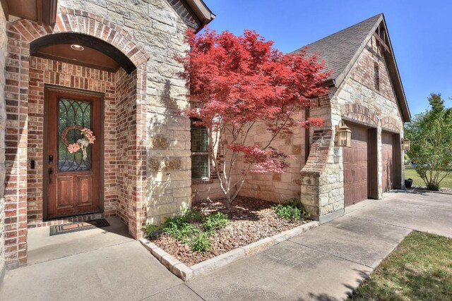 1706 Ambling Trl, Cedar Park, TX 78613 - property entrance featuring stone siding, brick siding, a garage, and concrete driveway
