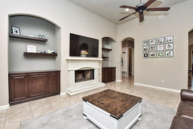 1706 Ambling Trl, Cedar Park, TX 78613 - living room with arched walkways, a ceiling fan, a fireplace with raised hearth, light tile patterned floors, and a high ceiling