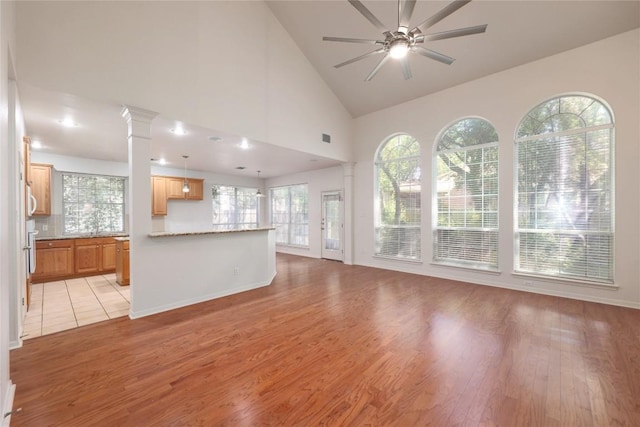 6008 Sierra Leon St, Austin, TX 78759 - unfurnished living room featuring ceiling fan, light wood-type flooring, high vaulted ceiling, and ornate columns