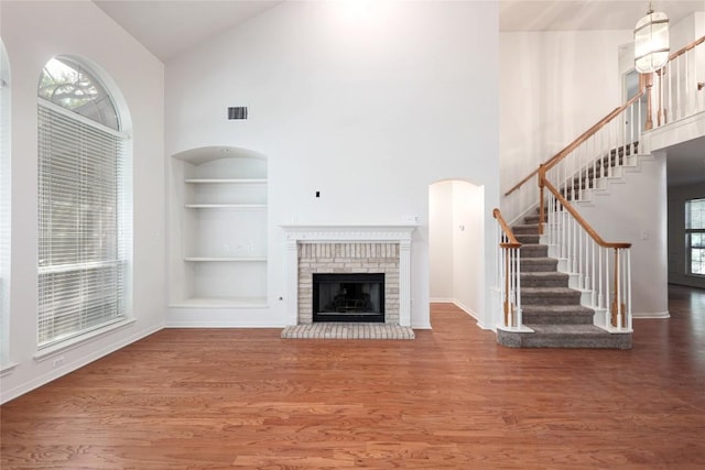 6008 Sierra Leon St, Austin, TX 78759 - unfurnished living room featuring high vaulted ceiling, built in features, wood finished floors, stairs, and a fireplace