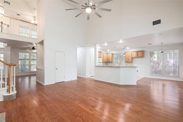 6008 Sierra Leon St, Austin, TX 78759 - unfurnished living room featuring ceiling fan, wood finished floors, a towering ceiling, stairs, and ornate columns