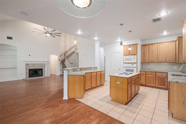 6008 Sierra Leon St, Austin, TX 78759 - kitchen with a kitchen island, white appliances, a ceiling fan, light wood finished floors, and a brick fireplace