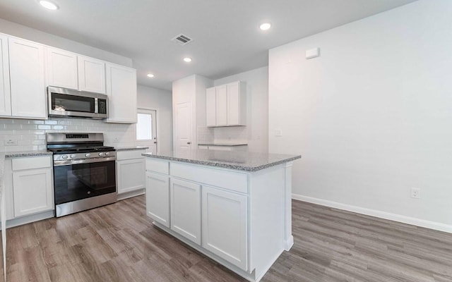 510 Timber Brook Dr, Hutto, TX 78634 - kitchen featuring white cabinets, stainless steel appliances, visible vents, light wood-style floors, and decorative backsplash