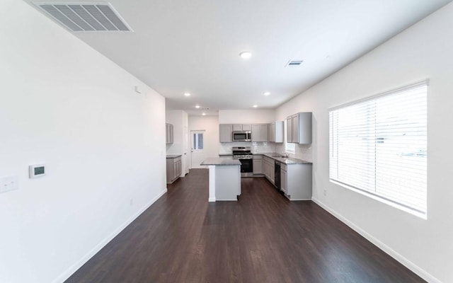 108 Biscayne Dr, Hutto, TX 78634 - kitchen with stainless steel appliances, visible vents, baseboards, gray cabinetry, and dark wood-style floors