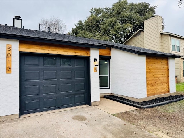 view of front facade featuring an attached garage, roof with shingles, concrete driveway, and brick siding