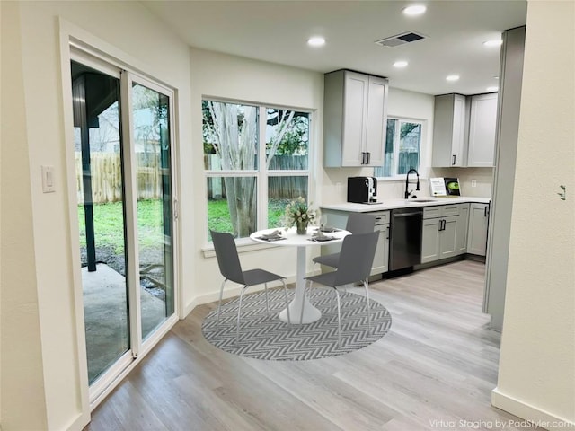kitchen with visible vents, dishwasher, a sink, light countertops, and light wood-style floors