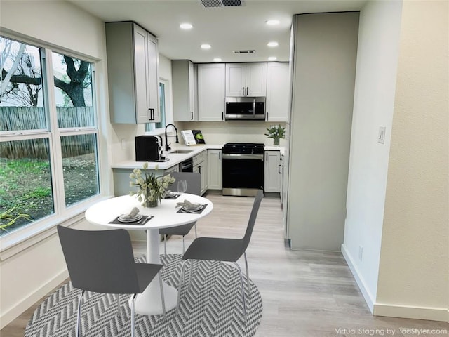 kitchen featuring range with gas cooktop, visible vents, stainless steel microwave, a sink, and baseboards