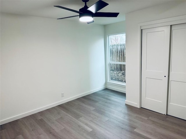 unfurnished bedroom with wood finished floors, ceiling fan, baseboards, and a closet