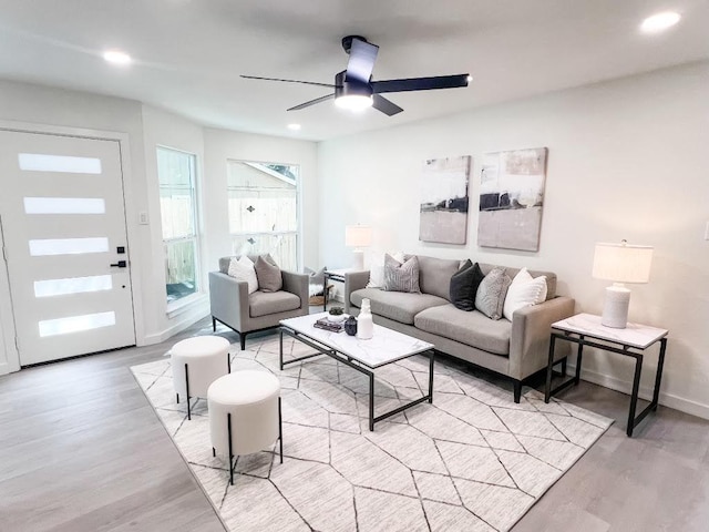 living room featuring light wood-style flooring, baseboards, a ceiling fan, and recessed lighting