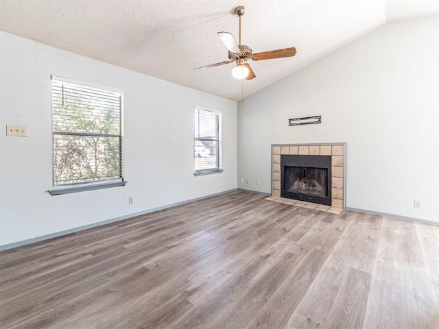 9624 Sugar Hill Dr Unit A & B, Austin, TX 78748 - unfurnished living room with vaulted ceiling, wood finished floors, ceiling fan, a tiled fireplace, and a textured ceiling
