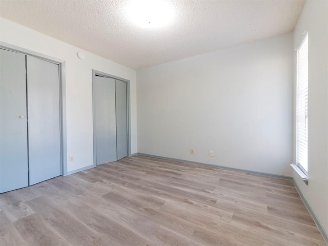 9624 Sugar Hill Dr Unit A & B, Austin, TX 78748 - unfurnished bedroom featuring multiple closets, light wood finished floors, multiple windows, and a textured ceiling